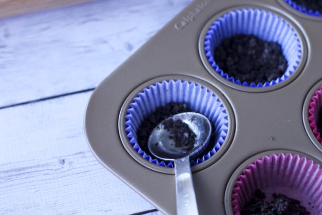 cookie crust inside cupcake liners with a spoon patting them down