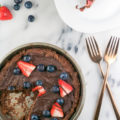 You haven't lived until you've tried this Flourless Chocolate Cookie Pizza recipe. A chocolate peanut butter cookie is smeared with dark chocolate and topped with fresh blueberries, strawberries, and sea salt for a delicious take on a gluten-free cookie pizza.