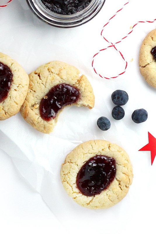 Celebrate this summer's patriotic holidays with these delightfully delicious and super simple Berry Coconut Thumbprint Cookies this year. Blueberry and cherry jam are served up on light and fluffy coconut cookies!