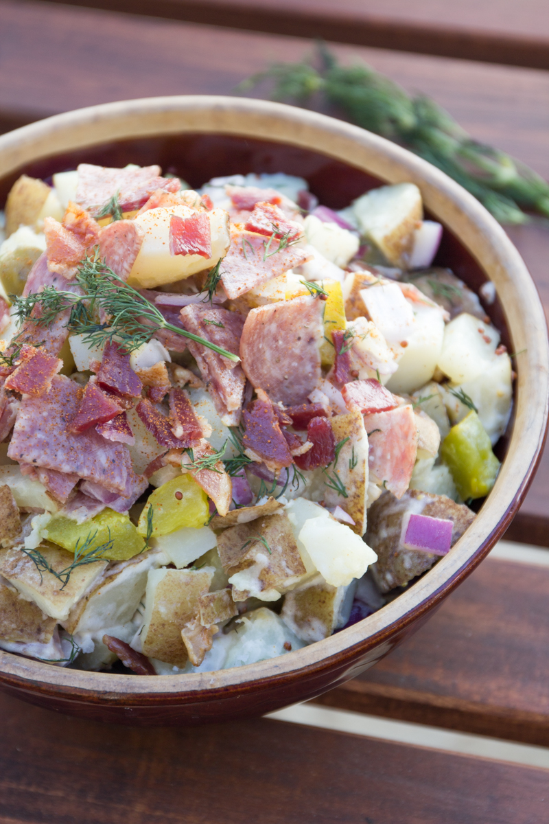 Dill pickles, bacon, and salami. These are essentials for one amazing summer potato salad. You won't need to bring back any leftovers if you make this Meaty Dill Pickle Potato Salad for your next barbecue.