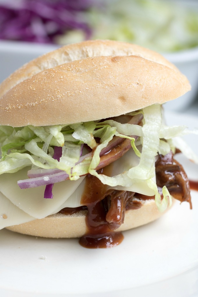 No one will be able to resist these Slow Cooker BBQ Slider Sandwiches! These savory BBQ Sliders are perfect for an easy dinner, potluck, or any gathering served with shaved lettuce, shaved crunchy red cabbage, red onion, and cheese.