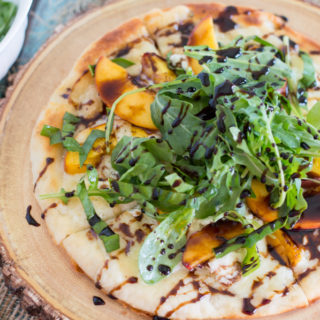 Fire up the grill and grab your best summer produce for this tasty GF Balsamic Glazed Grilled Peach Pizza recipe! Not only are we grilling the pizza, but the peaches too. Top it all off with spicy arugula and sweet balsamic glaze for the perfect gluten-free pizza!