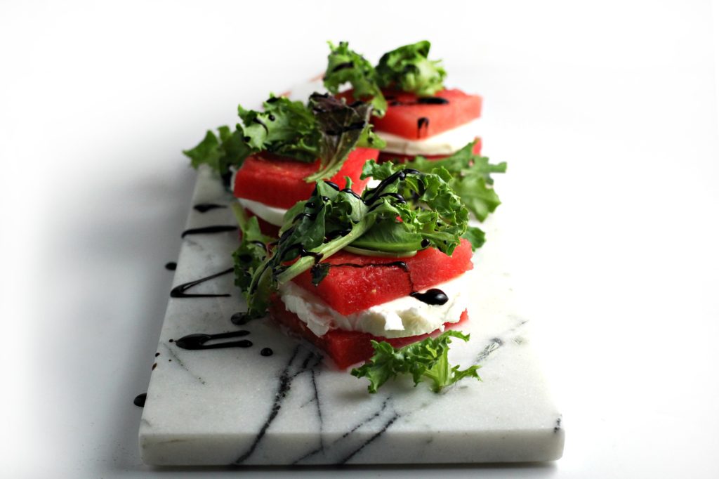 Impress your friends with this delectable, seasonal Balsamic Glazed Grilled Watermelon Stacked Salad recipe. The homemade balsamic glaze highlights the fresh flavors of the watermelon, arugula, and mozzarella.