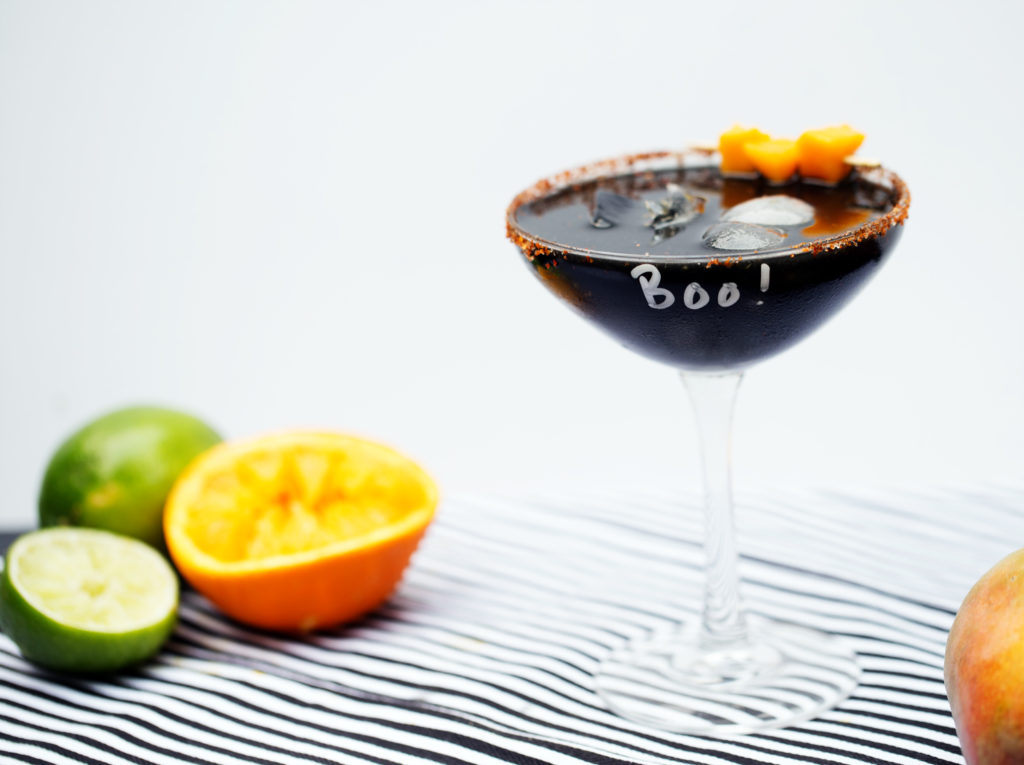 Celebrate the spookiest of holidays with this Mysterious Midnight Mango Margarita. Fresh mango purée, lime, and orange juice shaken with charcoal-infused tequila; this black-as-night cocktail is like the tropics in disguise!