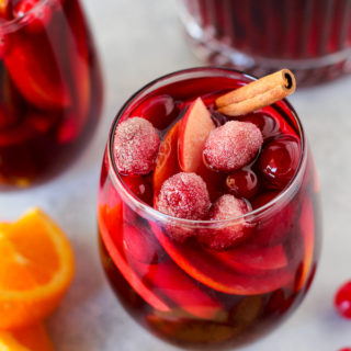 This Apple Cranberry Sangria recipe is loaded with seasonal produce. This red wine based holiday cocktail is perfect for entertaining guests! Red wine, apple brandy, cranberry juice, cinnamon sticks, apples, oranges, and fresh cranberries all work together to make this the tastiest sangria ever.
