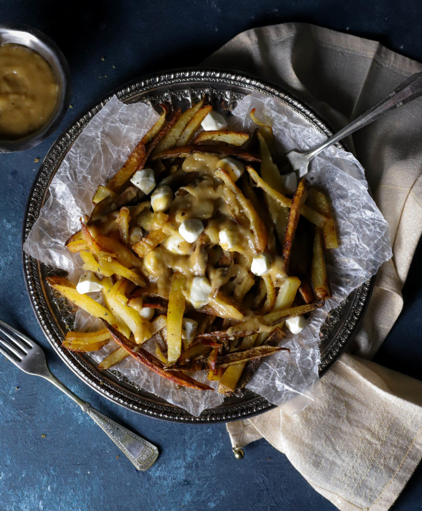Authentic Canadian Classic Poutine is a traditional Canadian appetizer that's so hearty, it can be served as a meal. Baked seasoned fries topped with cheese curds and homemade gravy is just the indulgence you need for cheat day, parties, or happy hour at home!