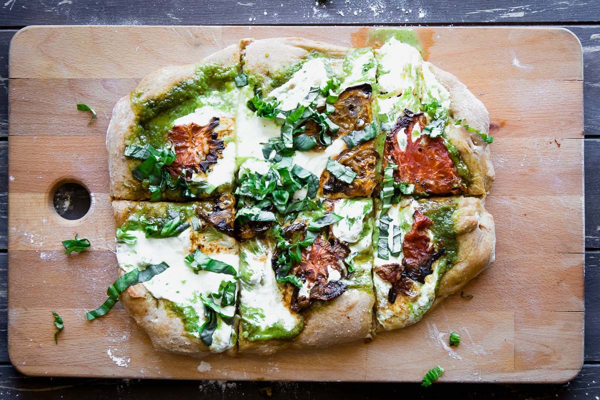 This Roasted Tomato Basil Pesto Pizza is perfect for pizza night at home. This healthier classic uses a whole wheat crust, herbed basil pesto, roasted heirloom tomatoes, and mozzarella to create a simple and satisfying vegetarian meal.