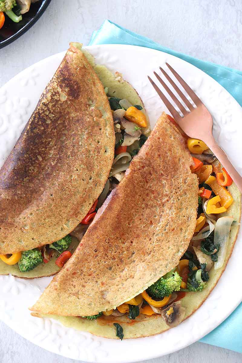 Sautéed Veggie Stuffed Lentil Crepes, aka Veggie Stuffed Moong Dal Chilla, are a cheap healthy meal to enjoy as a nutritious breakfast. This popular Indian vegetarian dish gets protein from the Moong Dal Lentils and vitamins and minerals from the mixed veggies.