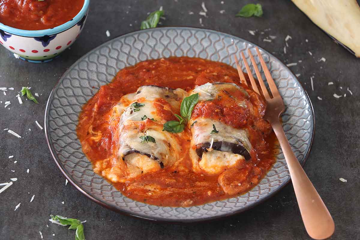This low-carb, 5-Ingredient Eggplant Rollatini is a healthy comfort food that's perfect for a weeknight dinner. This healthier classic is made with grilled eggplant slices that are filled with ricotta, mozzarella, and parmesan cheeses, then topped with marinara sauce.