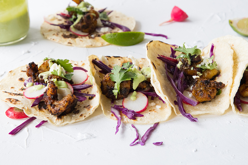Light and crispy, these Shrimp Tacos with red cabbage slaw and a homemade avocado cilantro sauce are a cheap healthy meal that's perfect for a weeknight dinner, summer entertaining, or a date night in.