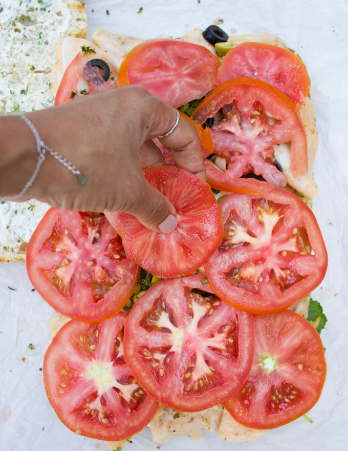 adding tomatoes to the sandwich