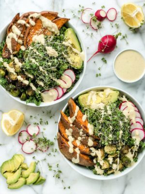 This Sweet Potato Kale Bowl is an upgraded kale salad that's perfect for a simple weeknight dinner. This 30-minute meal with roasted sweet potatoes, brussels sprouts, avocado, radish, micro greens, and tangy tahini dressing is the ultimate vegetarian dish.