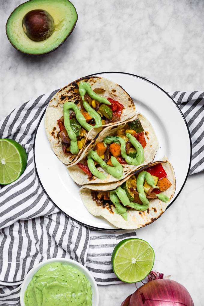 Learn to make these Roasted Veggie Tacos with Avocado Crema like a pro to impress dinner guests. This cheap healthy meal is a vegetarian dinner full of vibrant colors and flavors.
