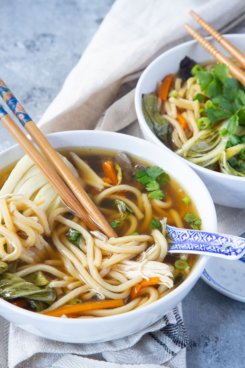 This Slow Cooker Asian Chicken Noodle Soup is what comfort food dreams are made of. An easy weeknight dinner with fall-apart shredded chicken, thick noodles, and fresh veggies. This Crock Pot soup is perfect for the cooler evenings!