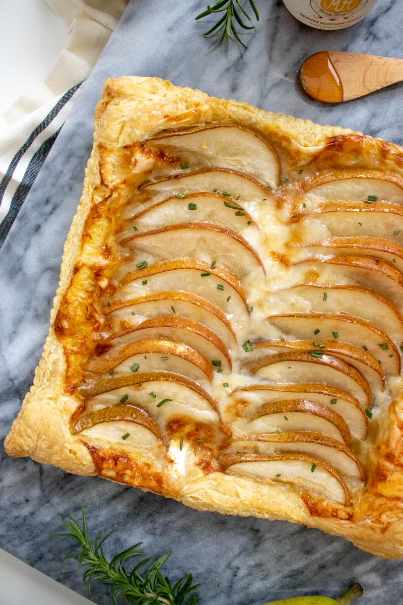 This Sweet + Savory Pear Goat Cheese Tart is the perfect 6-ingredient appetizer. If you're entertaining guests, this seasonal appetizer has everything you need with a flaky crust topped with goat cheese, Bartlett Pears, rosemary, and honey.
