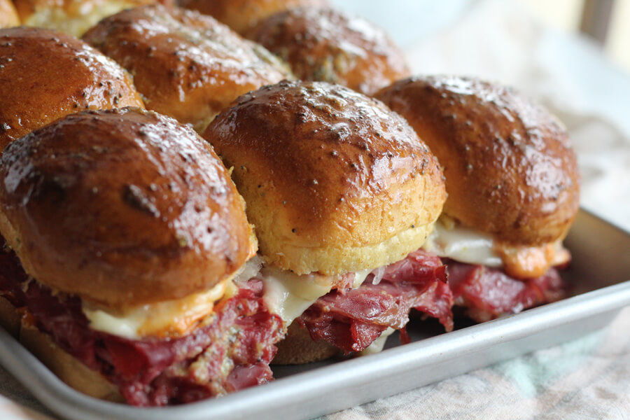 Looking for a hearty, 30-minute appetizer for game day? These Reuben Slider Sandwiches are made with classic corned beef, sauerkraut, cheese, and a zippy sandwich sauce. These mini deli-style sandwiches are an easy appetizer that will impress a crowd!