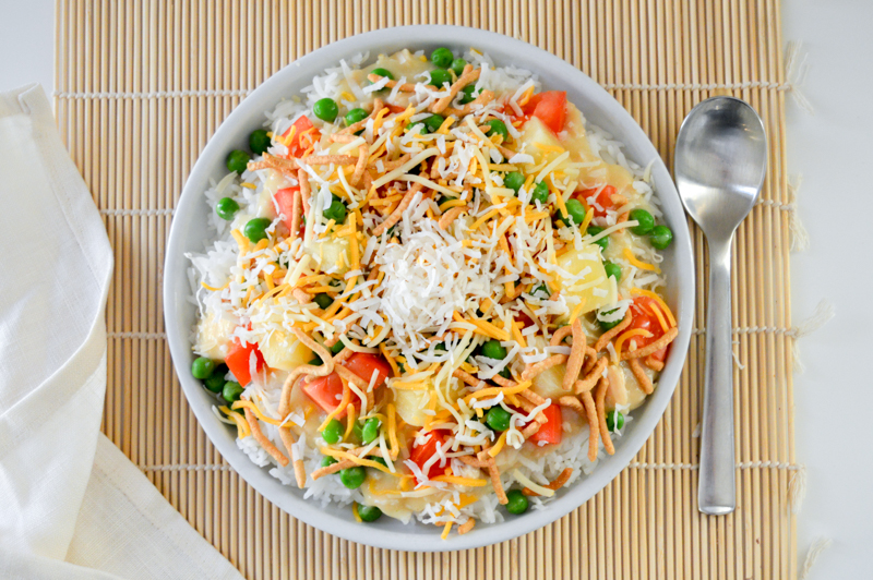 Chicken Hawaiian Haystacks is a 30-minute meal with a rice base topped with chicken gravy, chopped tomatoes, peas, pineapple, chow mein noodles, cheese, and coconut flakes. This budget-friendly dish is a one-pot, 4-person $10 meal that's comfort food at its finest.
