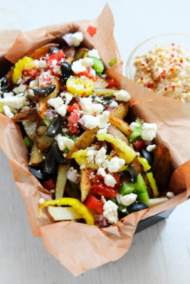 Crispy fries are topped with salty feta and Mediterranean veggies in this food truck inspired appetizer. These loaded Greek Street fries with zesty feta dip are a street food indulgence.