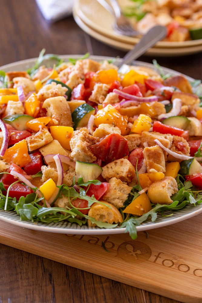 Classic Italian Tuscan Panzanella Bread Salad is made with cubes of crusty bread, farmers market fresh ripe tomatoes, cucumbers, red onions, and basil. All tossed in a fragrant basil pesto vinaigrette.