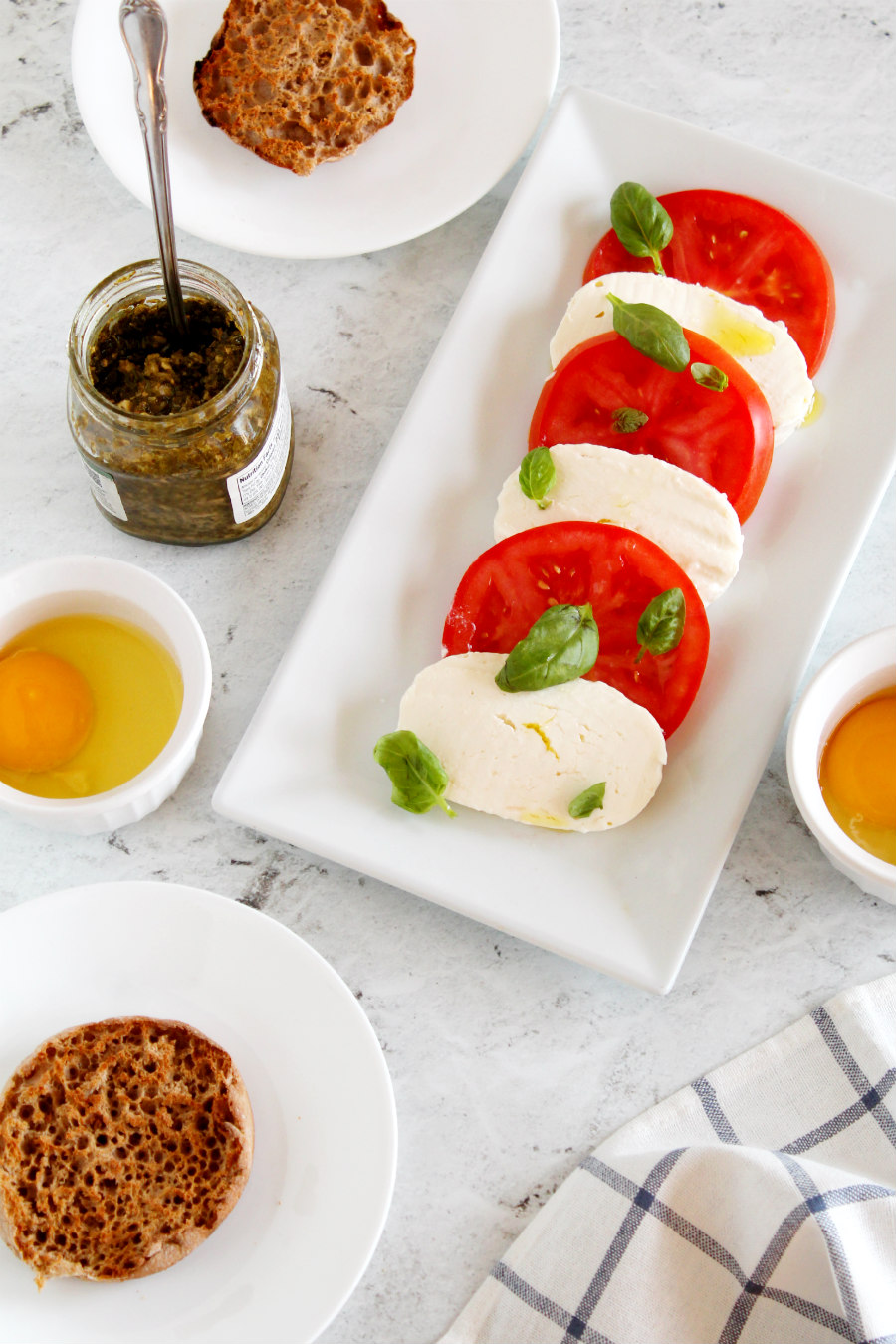 If you enjoy the traditional Italian flavors of Caprese Salad, you'll love this Poached Eggs Caprese recipe. Poached eggs on English muffins with tomato, basil, pesto, and fresh mozzarella for a hearty breakfast or Sunday brunch!