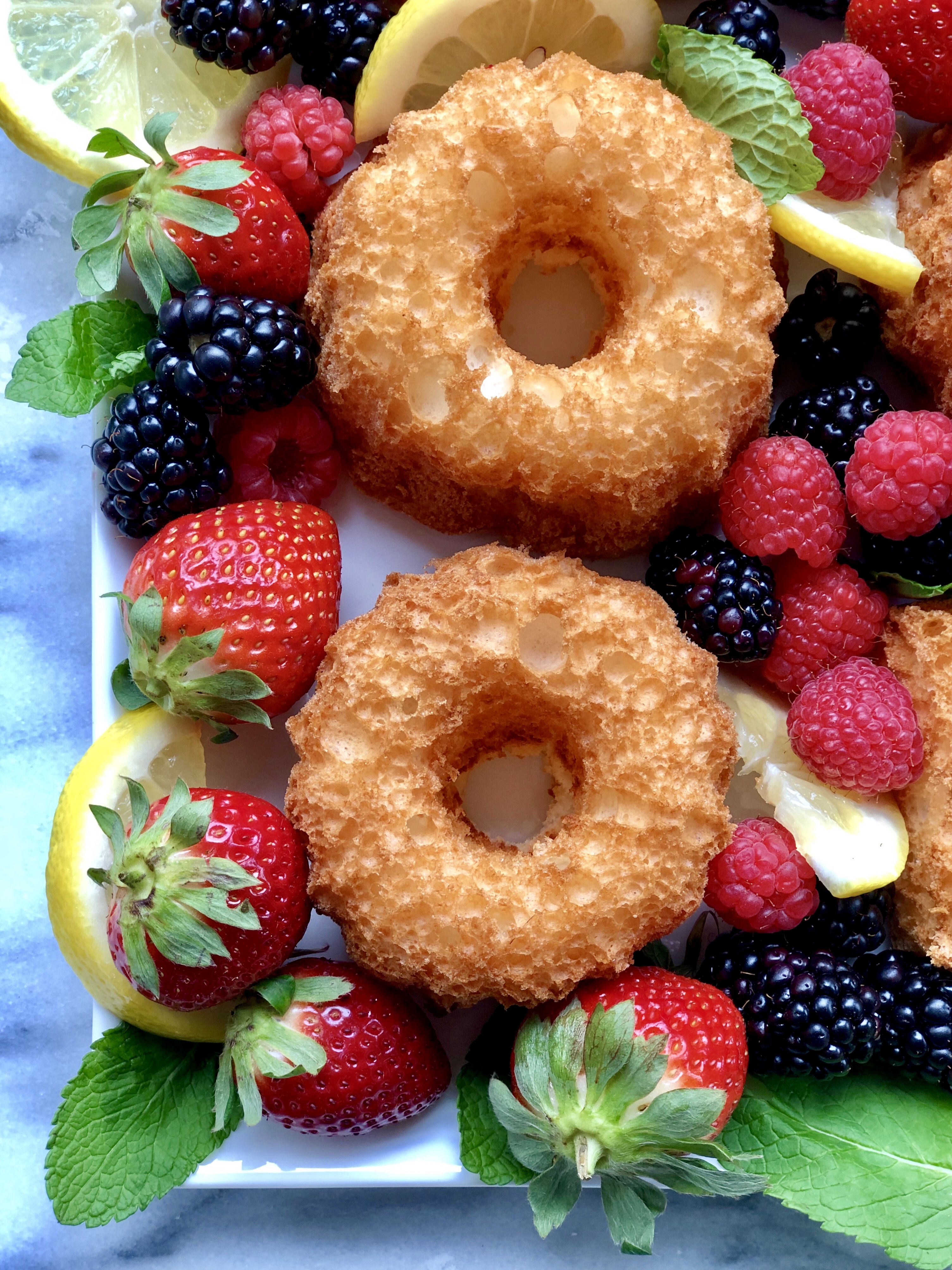 Light in flavor and topped with fresh farmers market fruit and lemon whipped cream, this Lemon Angel Food Cake Platter is perfect for warm-weather entertaining. A no-cholesterol cake recipe that's a healthier dessert option when you're craving something sweet.