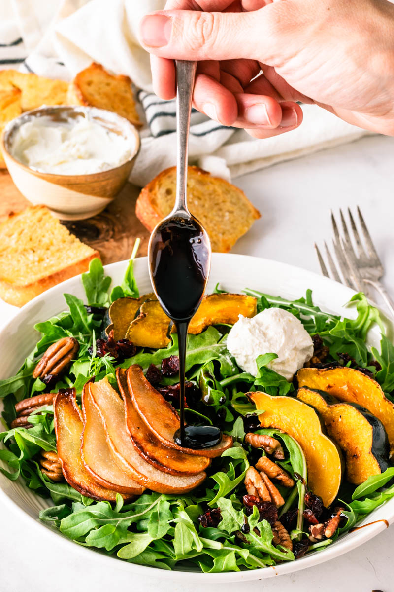 Roasted Pear Squash Winter Salad is a satisfying make-ahead meal. Roasted pears and acorn squash lay on a bed of arugula sprinkled with pecans, dried cranberries, and whipped goat cheese. A drizzle of homemade balsamic reduction rounds it out for the perfect meal!